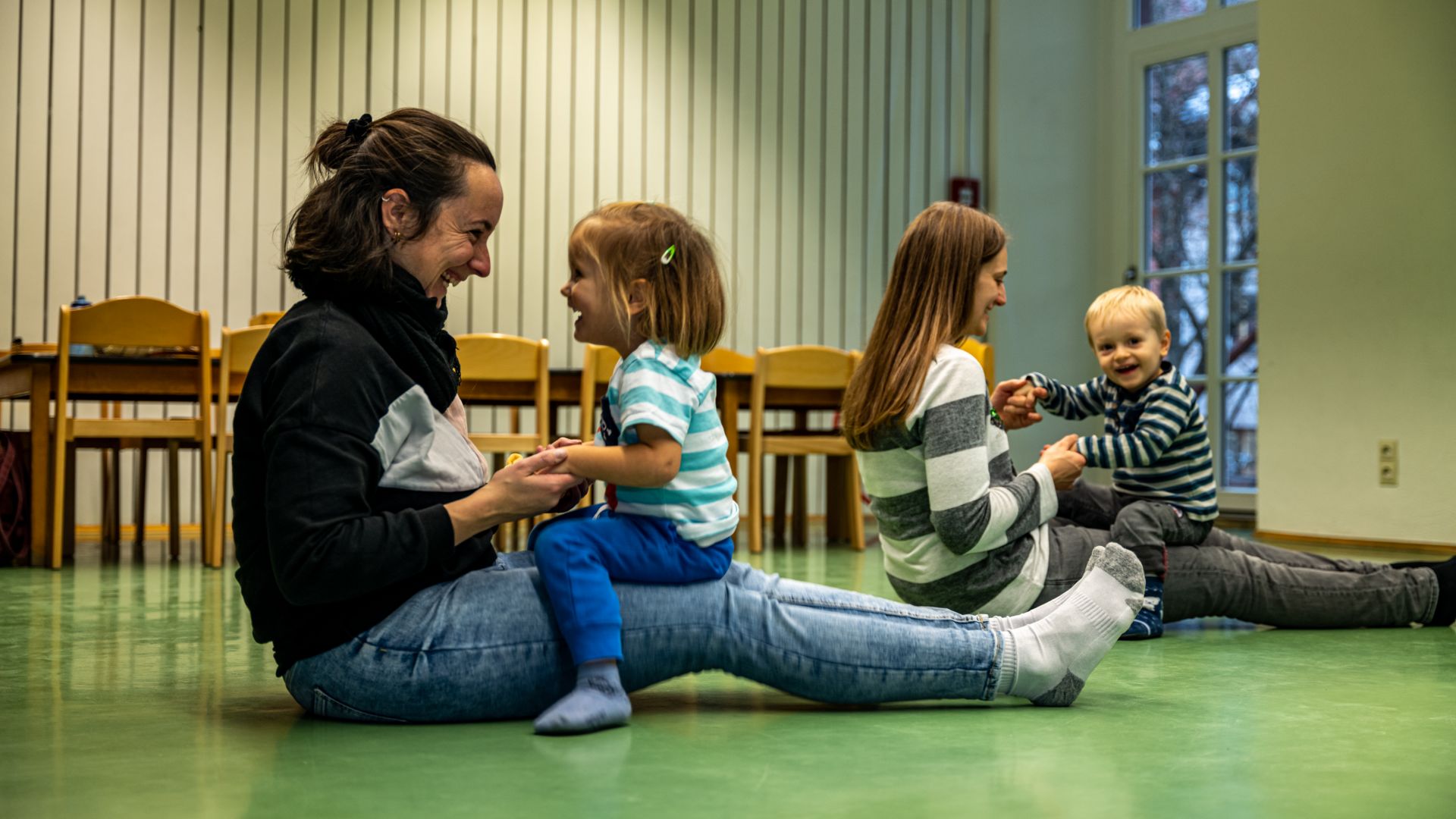 Zwei Mütter sitzen auf dem Boden mit ihren Kindern auf dem Schoß